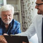 an elderly couple is shaking hands with a man while looking at a clipboard