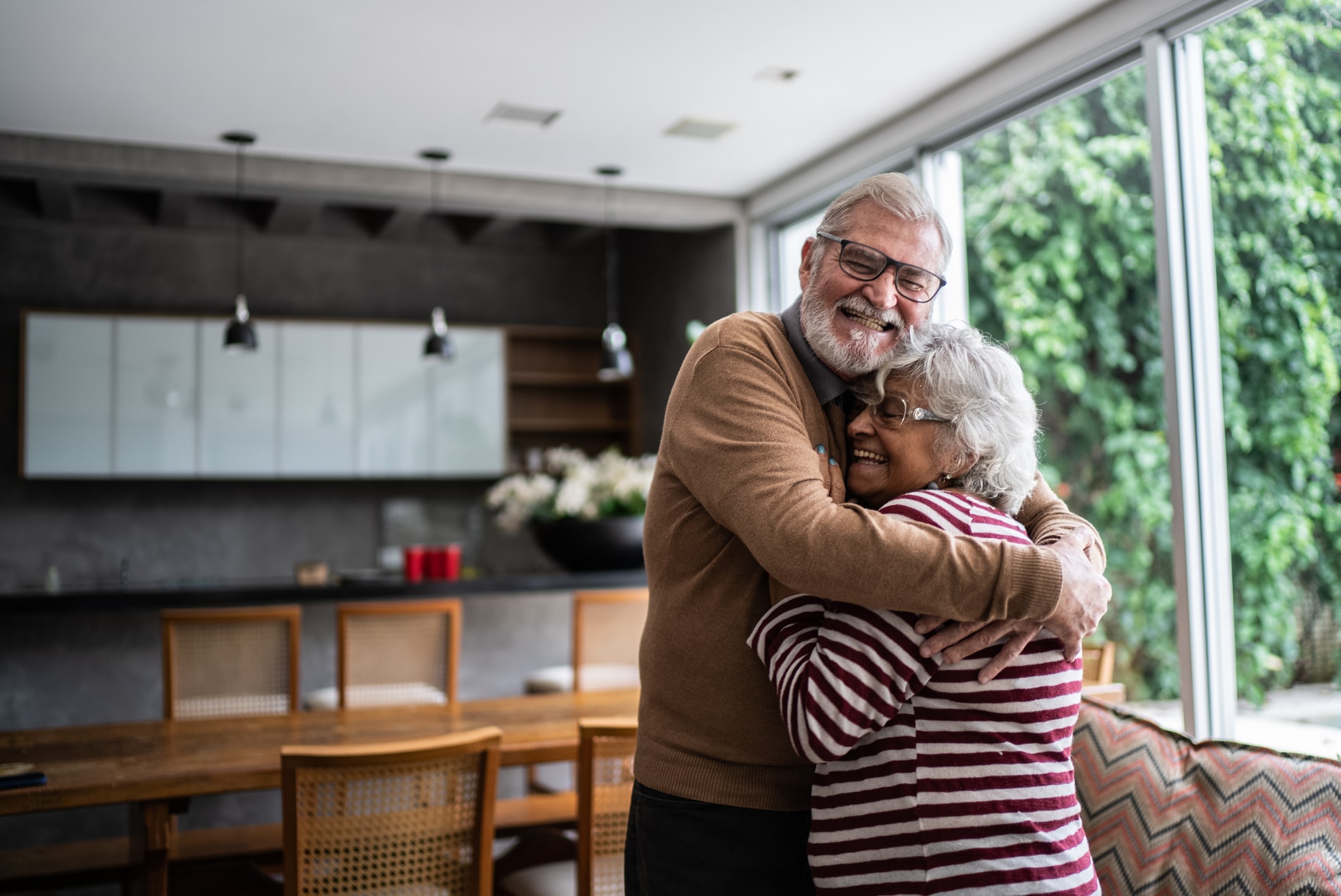 an elderly couple hugging each other in a living room