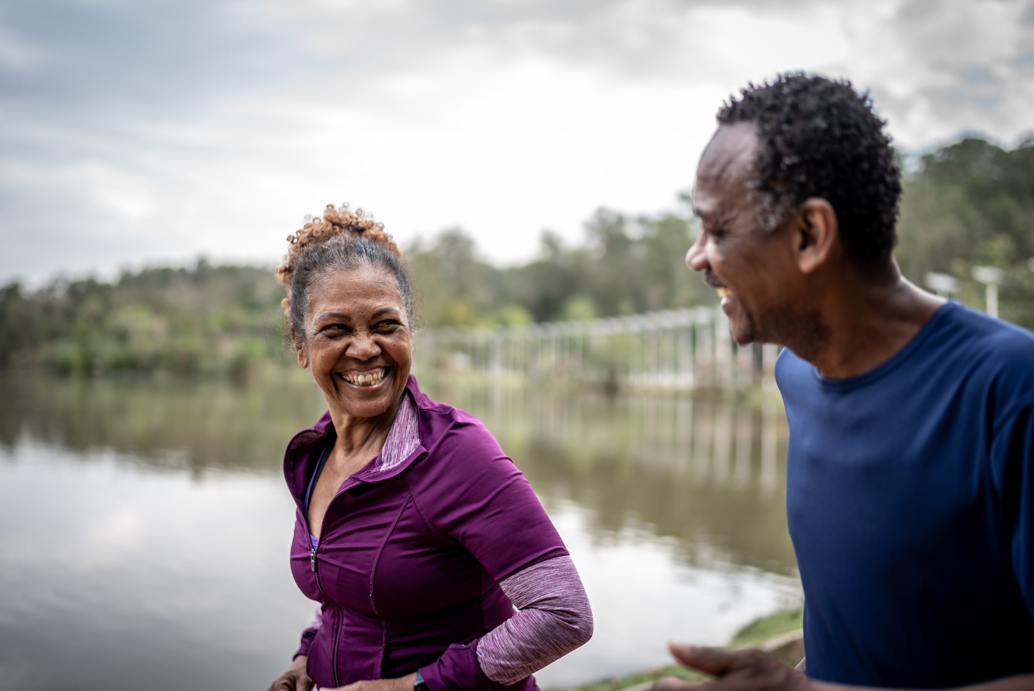 a man and a woman are laughing by a lake