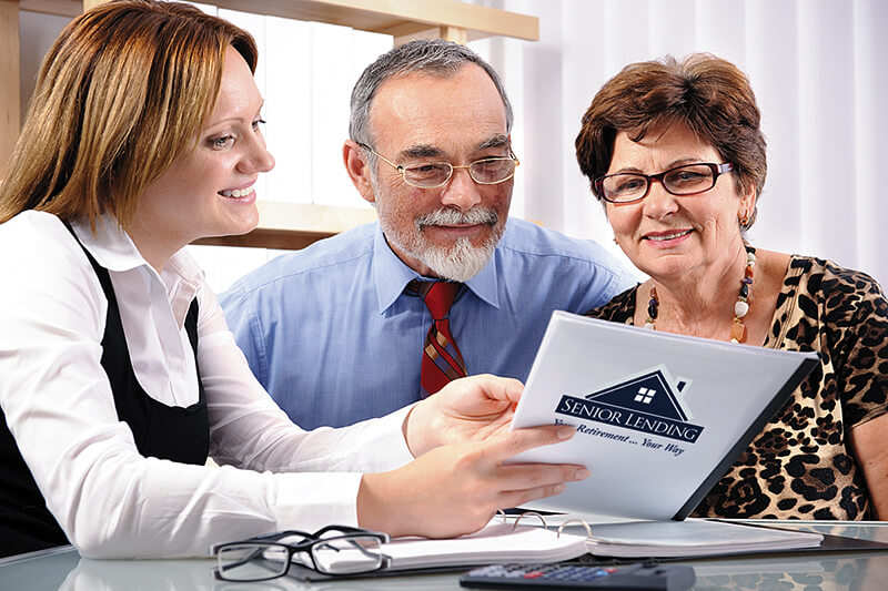 a senior couple looking at reverse mortgage information with a representative