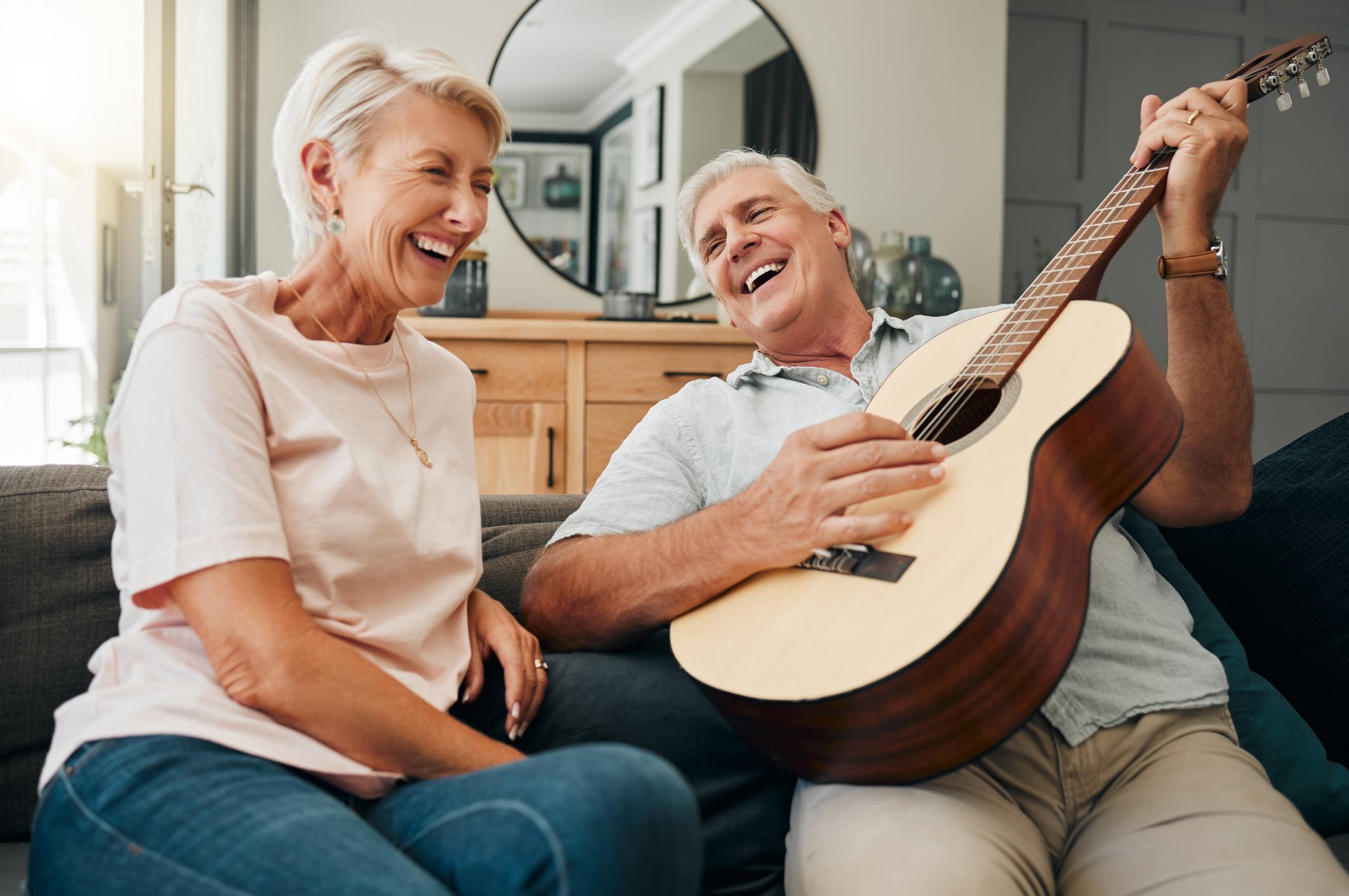 a man is playing a guitar for his wife who is laughing