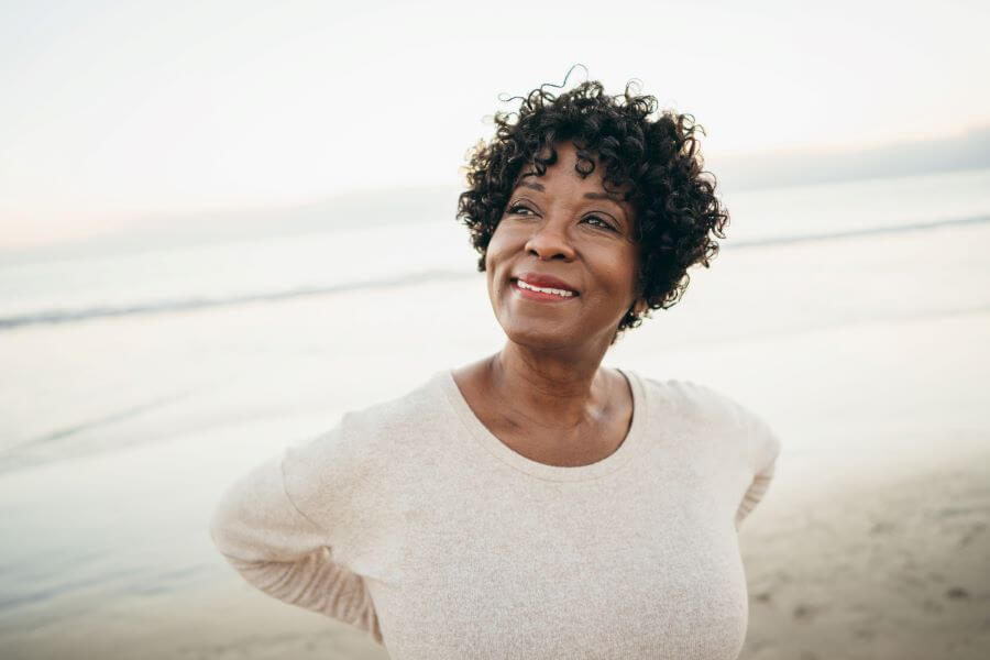 a woman with curly hair is smiling on the beach
