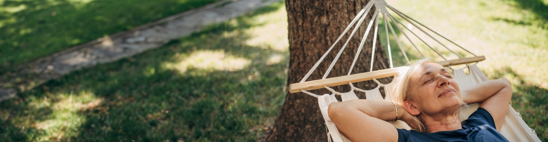 a woman is laying in a hammock under a tree