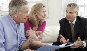 a man in a suit is talking to a woman and a man in a blue shirt about reverse mortgage