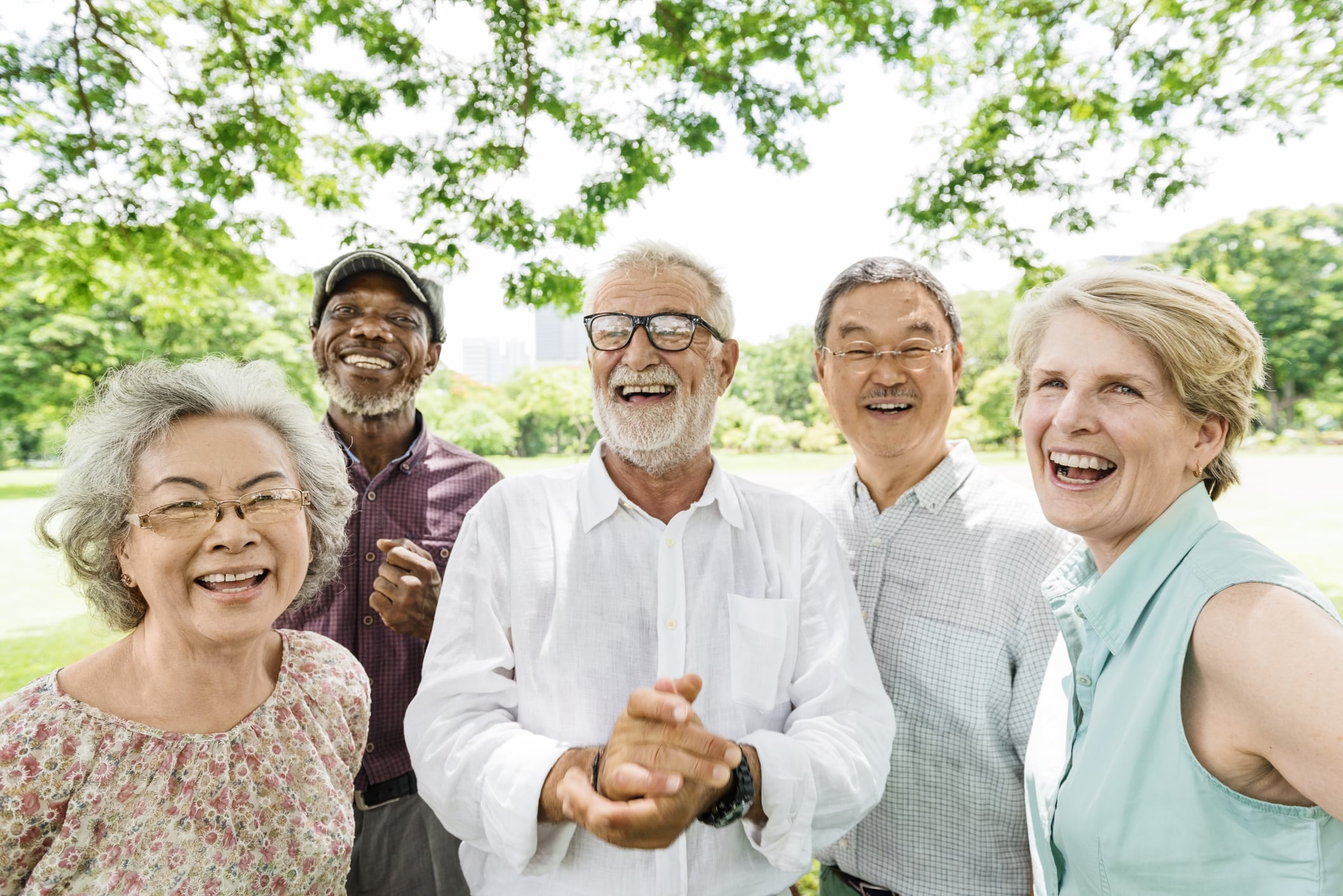 a group of elderly people are smiling and holding hands in a park