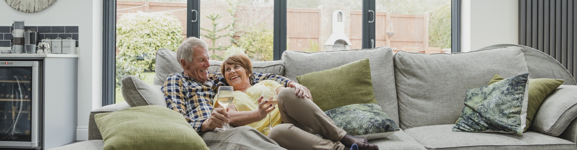 a man and woman sit on a couch holding wine glasses